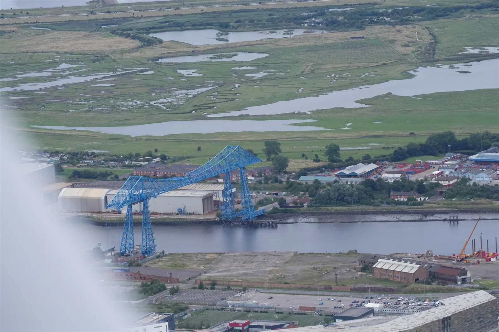 Aerial photograph of a riverside industrial port with large blue cranes